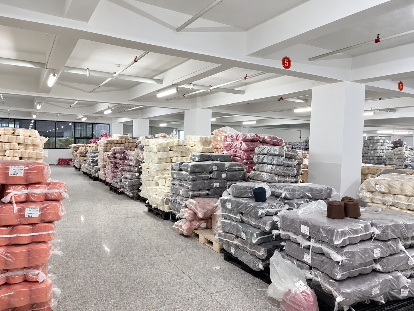 纱线现货仓库全景,多色纱线按批包装堆放。